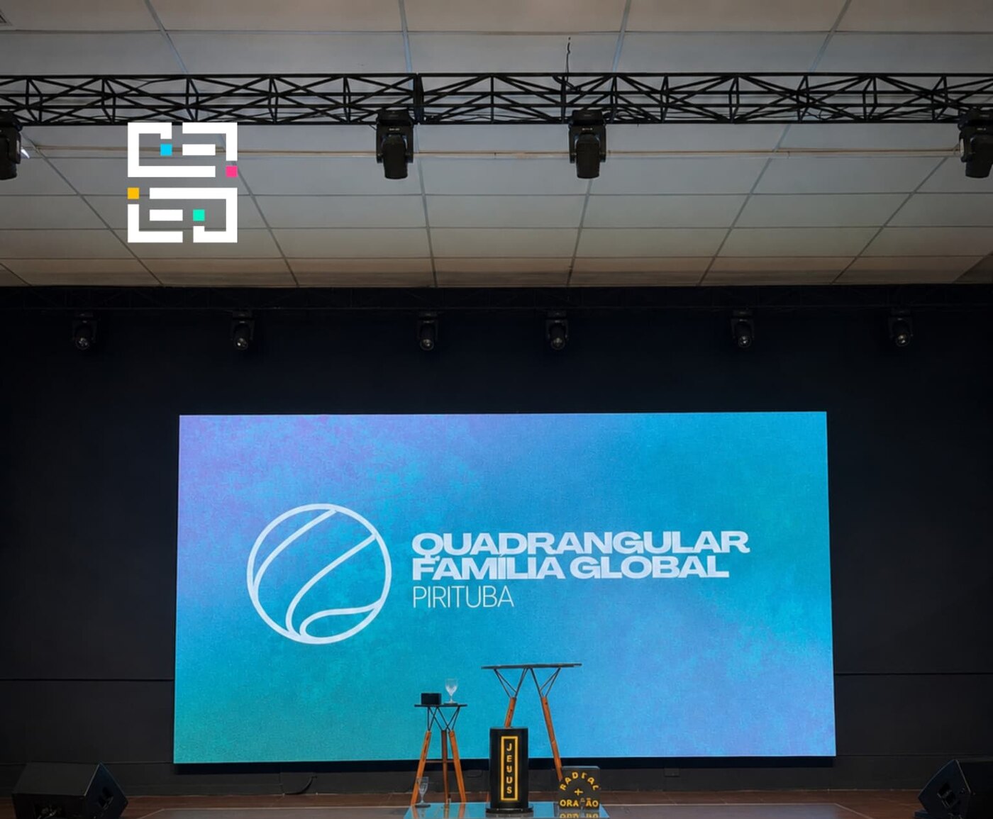 Painel de LED instalado atrás do palco de um templo com plateia sentada